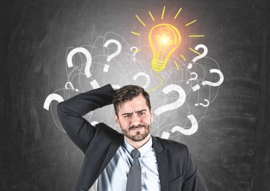 Portre karışık düşüncenin kafa onun ayakta blackboard pek çok soru işaretleri ve ampul üzerinde çizilmiş yakınındaki tırmalamak işadamı sakallı. İş fikir kavramı.