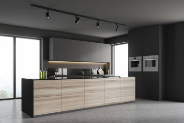 Corner of modern kitchen with gray walls, concrete floor, gray countertops and cupboards, wooden and gray island and two ovens in the wall. 3d rendering