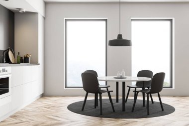 Interior of modern kitchen with white walls, wooden floor, loft windows, white countertops with built in stove and round table with gray chairs. 3d rendering