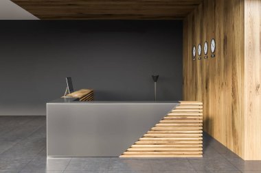Side view of stylish gray and wooden reception desk with computer standing in modern office with gray and wooden walls and clocks. 3d rendering