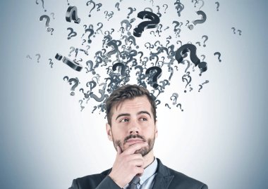 Takım elbise ayakta gri duvar başını ortaya çıkan pek çok soru işaretleriyle yakındaki sakallı düşünceli genç işadamı portresi. Çözüm arama kavramı