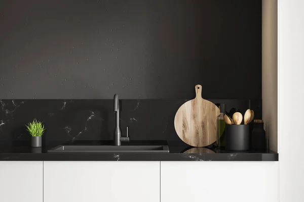 Black marble kitchen sink standing on white countertop in room with black walls. Wooden round cutting board and little potted plant. 3d rendering