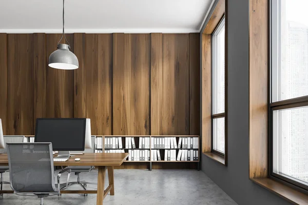 Interior of office workplace with dark wooden and gray walls, concrete floor and dark wooden computer tables. Shelves with folders near the wall. 3d rendering