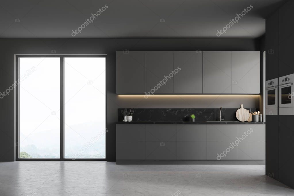 Interior of modern kitchen with gray walls, concrete floor, gray cupboards, countertops with built in sink and two ovens in the wall. 3d rendering