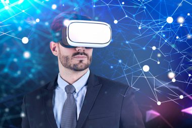 Ağ arabirimi ile koyu mavi arka plan üzerinde duran vr gözlüklü sakallı ciddi genç iş adamı. Çift tonlu görüntü pozlaması