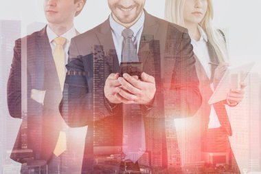 İşadamı smartphone ile gülümseyen, sarışın meslektaşı ile boşaltmak ve ciddi adamla birlikte şehirde ayakta silah geçti. Yöneticisi iş kavramı. Çift tonlu görüntü pozlaması
