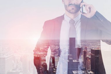 Tanınmayan portresi koyu takım elbise ve Smartphone'da cityscape arka plan üzerinde konuşan işadamı sakallı. Çift tonlu görüntü pozlaması