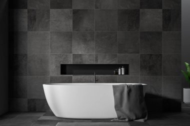 Close up of stylish bathroom interior with black tile walls and floor, white bathtub with gray towel hanging on it and gray rug. 3d rendering clipart
