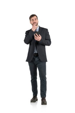 Takım elbise ve akıllı telefon tutarak sakallı düşünceli genç işadamı portresi izole tam uzunlukta.