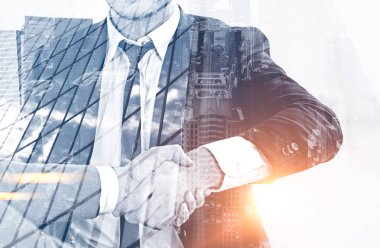 Gri cityscape arka plan üzerinde el sıkışan iki tanınmaz işadamlarından kapatın. İşbirliği kavramı. Çift tonlu görüntü pozlaması