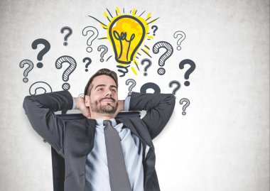 Sakallı koltuk pek çok soru işaretleri ve parlak ampul üzerinde çizilmiş beton duvarının yakınında oturan rahat genç iş adamı. İş fikri kavramı