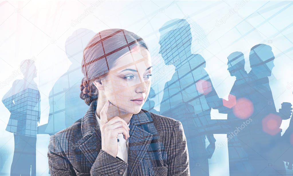 Pensive young businesswoman with dark hair wearing coat standing over skyscrapers background with double exposure of her colleagues. Leadership concept. Toned image