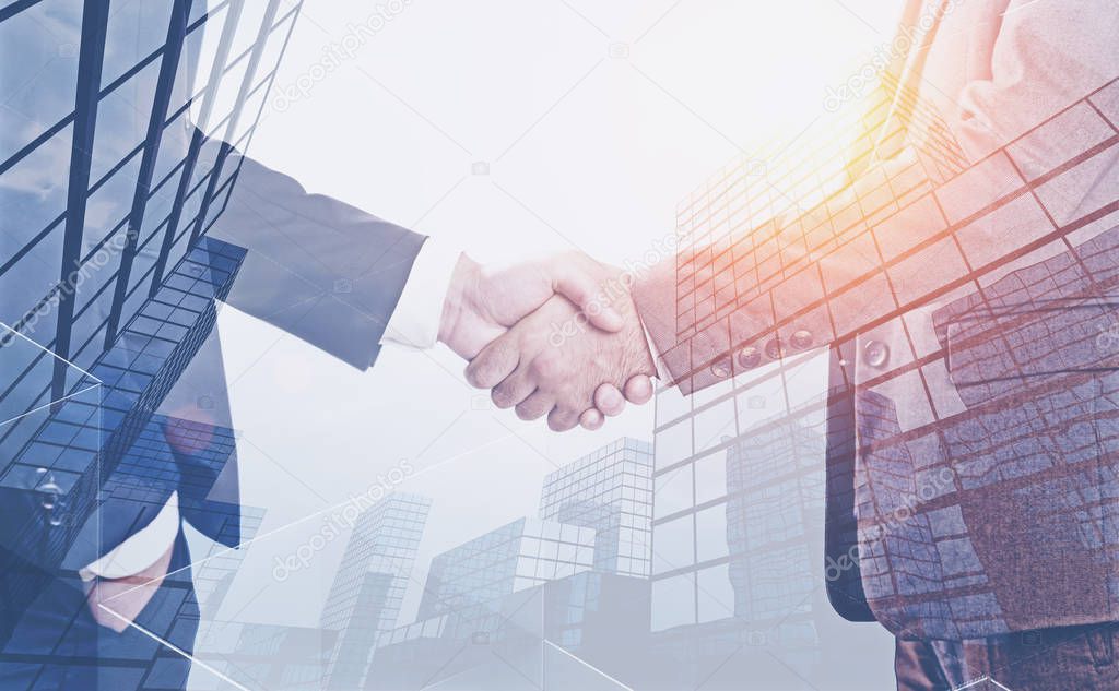 Two unrecognizable businessmen shaking hands over skyscraper background. Concept of business partnership. Toned image double exposure