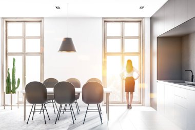 Beyaz ve gri duvarlar, petek desen kat, ışık gri mutfak tezgahı ve siyah sandalye ile beyaz masa mutfak iç kadında. Tonlu görüntü