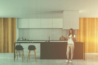 Beyaz duvarları, taş zemine, beyaz mutfak tezgahı, ahşap dolapları ve gri bar tabureleri ile modern mutfak iç kadında. Çift tonlu görüntü pozlaması