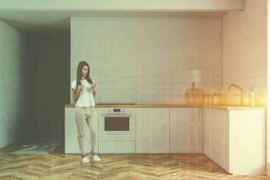 Kadın iç ahşap zemin beyaz duvarlı küçük mutfak ile beyaz mutfak tezgahı fırın ve lavabo ve bir kapı inşa. Çift tonlu görüntü pozlaması