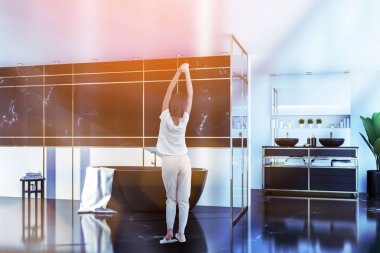 Siyah ve beyaz mermer duvarlar ile şık banyo iç kadın siyah siyah tezgah üzerinde duran çift lavabo ve küvet. Tonlu görüntü