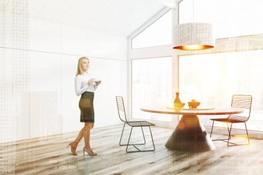 Kadın tavan yemek odası beyaz duvarlar ve tavan, ahşap zemin, büyük pencere, metal sandalyeler ve büyük tavan lambası ile yuvarlak masa ile köşesinde. Çift tonlu görüntü pozlaması