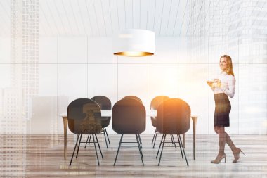 İç tavan yemek odası beyaz duvarlar ve tavan, ahşap zemin ve uzun masa üstündeki büyük tavan lambası ile gri sandalye ile bir kadın. Çift tonlu görüntü pozlaması