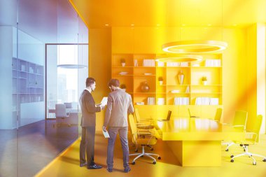 Office konferans salonu ile sarı duvarlar ve zemin, sarı sandalye ve sarı kitaplık uzun tabloyla iç konuşan iki iş adamları. Tonlu görüntü