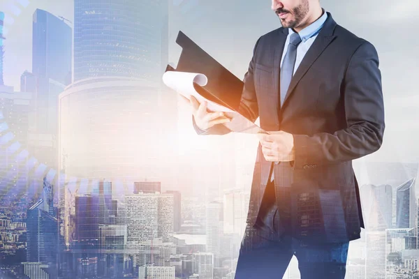 Unrecognizable Bearded Businessman Clipboard Standing Morning Cityscape Background Toned Image — Stock Photo, Image