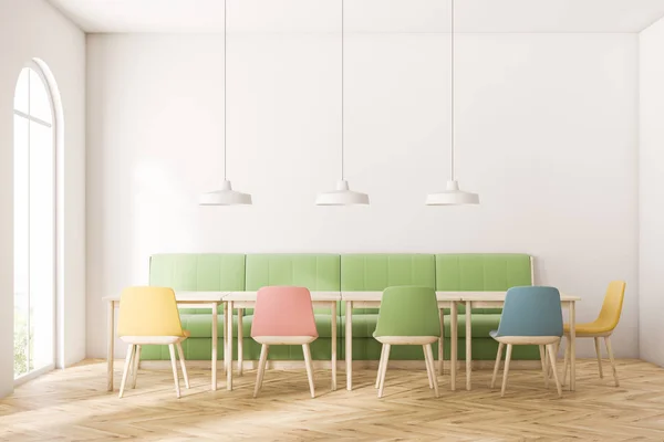 现代咖啡馆的内部 白色的墙壁 木地板 拱形的窗户 长长的绿色沙发和方形的木桌与柔和的彩色椅子 — 图库照片