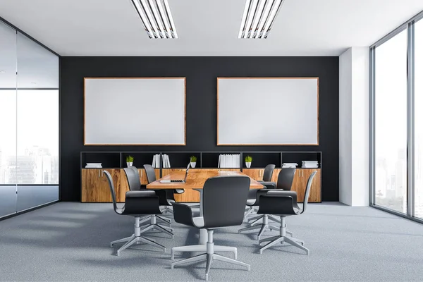 Interior of meeting room with black and white walls, carpet on the floor, long wooden table with black chairs and two horizontal posters. 3d rendering mock up