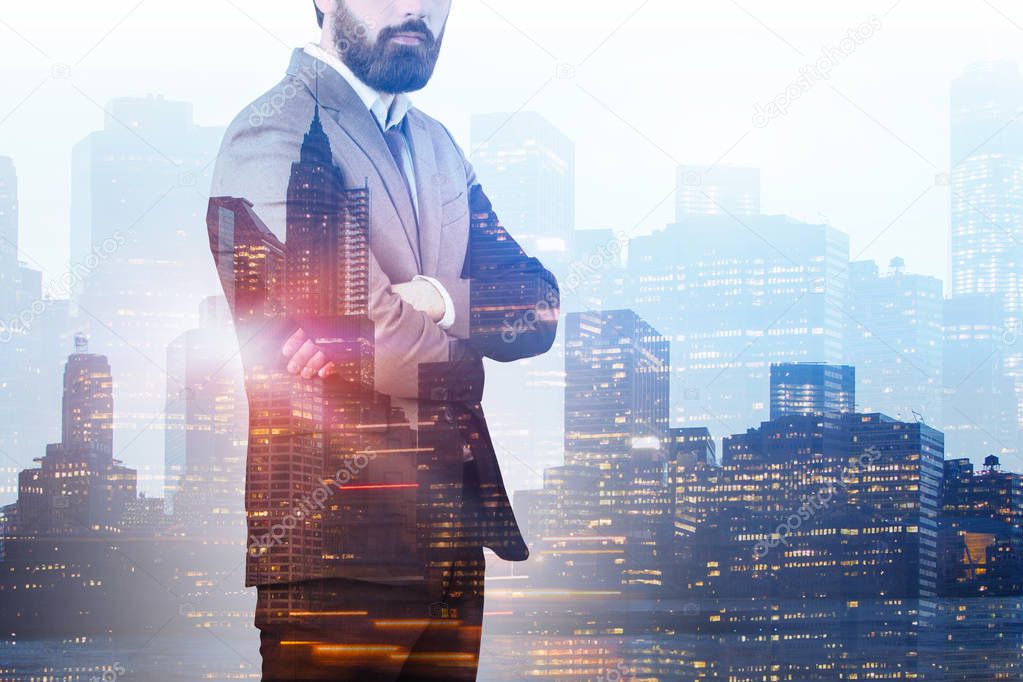 Unrecognizable confident business leader wearing brown suit standing with crossed arms over night cityscape background. Concept of leadership. Toned image double exposure