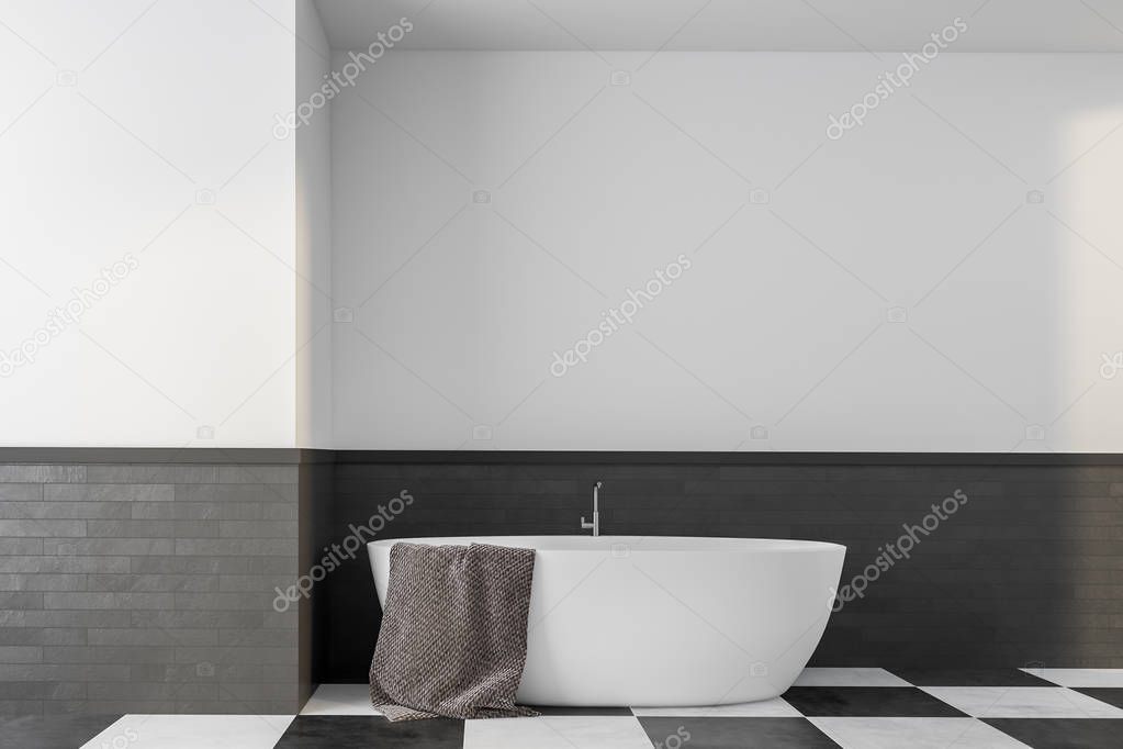 Interior of minimalistic bathroom with white and gray brick walls, tiled floor and white bathtub with gray towel hanging on it. 3d rendering