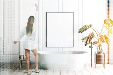 Minimalist banyo beyaz duvarlar, ahşap zemin, yukarıda ve saksı bitki dikey posteri asılı beyaz banyo küvetinde iç kadında. Tonlu görüntü pozlama sahte katlayın