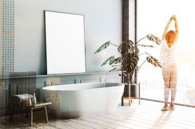 Kadın gri duvarlar, ahşap zemin, yukarıda ve saksı bitki dikey posteri asılı beyaz banyo küvetinde minimalist banyo köşesinde. Tonlu görüntü pozlama sahte katlayın