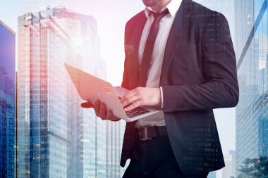 Tanınmayan genç işadamı laptop ile cityscape arka plan üzerinde çalışıyor. İş yaşam tarzı kavramı. Çift tonlu görüntü pozlaması