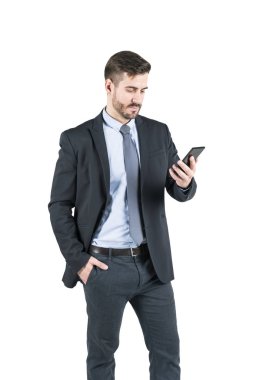 İzole sakal onun smartphone vasıl seyir koyu takım elbise ile ciddi genç işadamı portresi