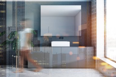 Gri taş duvarlar, beton zemin, gri tezgah ve yatay ayna üzerinde duran lavabo banyo iç kadında. Tonlu görüntü çift pozlama bulanık