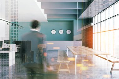 İç açık alan Office yeşil ve beyaz duvarlar, beton zemin, bilgisayar masaları, gri resepsiyon masası ve banklar ile uzun tablo satırları ile iş adamı. Çift tonlu görüntü pozlaması bulanıklık