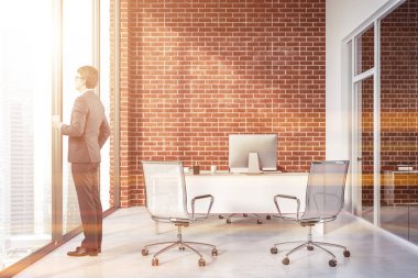 Müdür ofis tuğla duvarlar, beyaz zemin, panoramik pencere, beyaz bilgisayar masa sandalye ziyaretçi ve cam kapı ile iç'iş adamıdır. Tonlu görüntü
