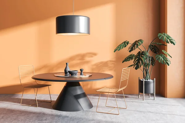 Interior of minimalistic dining room with orange walls, concrete floor, gray round table with orange metal chairs, stylish ceiling lamp and potted plant. 3d rendering