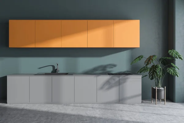 Interior of minimalistic kitchen with green walls, concrete floor, orange cupboards and gray countertops with built in sink and cooker. 3d rendering