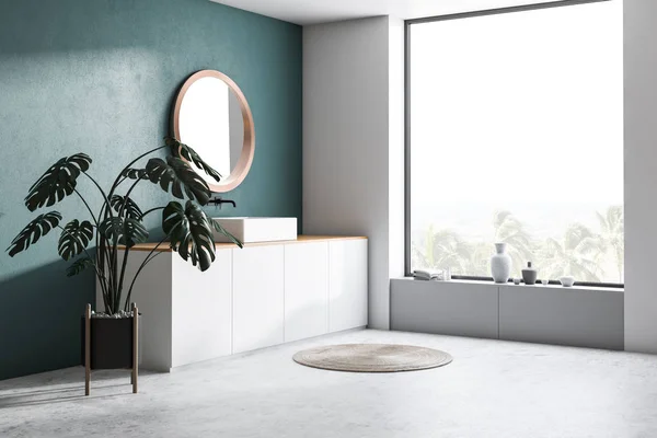 Corner of modern bathroom with dark green walls, concrete floor, sink standing on white countertop and round mirror. 3d rendering