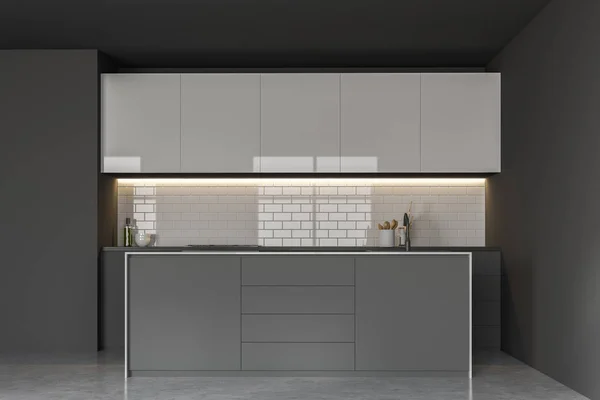 Interior of minimalistic kitchen with gray walls, concrete floor, gray countertops with cooker, white cupboards and gray island with built in sink. 3d rendering
