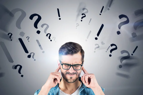 Hombre con gafas cubriendo orejas, signos de interrogación blanco — Foto de Stock