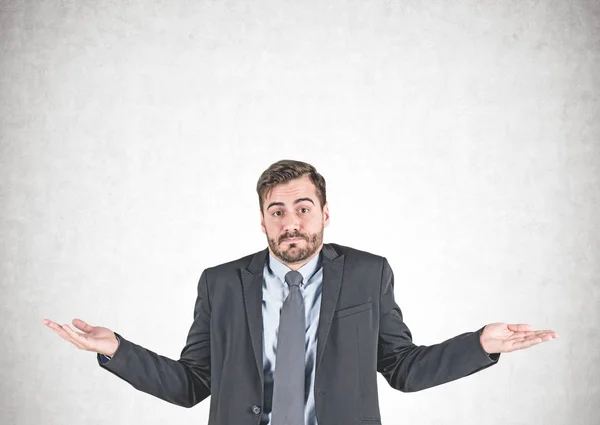 Young businessman shrugging shoulders, concrete — Stock Photo, Image