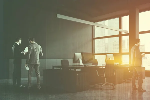 Бізнесмени в кутку сірого відкритого простору офісу — стокове фото