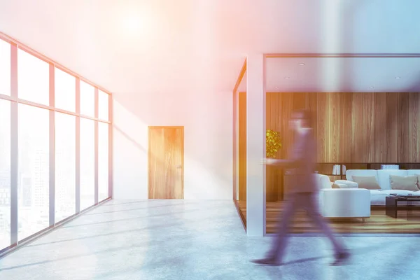 Man in corridor with lounge area in white office