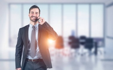 Toplantı salonunun içinde smartphone cep telefonu ile gülümseyen iş adamı