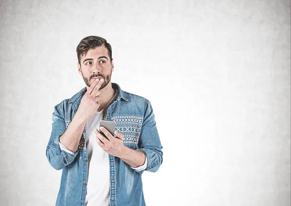 Nachdenklicher junger Mann mit Smartphone, Beton — Stockfoto