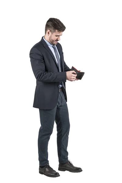 Junger bärtiger Mann im Anzug blickt in seine leere Brieftasche. — Stockfoto