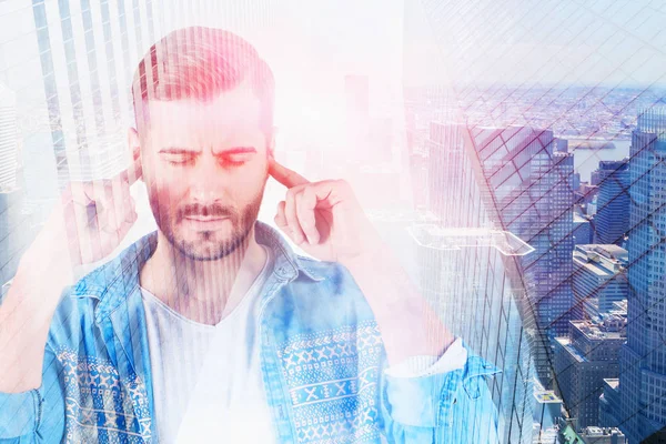 Stressed casual man in city covering ears