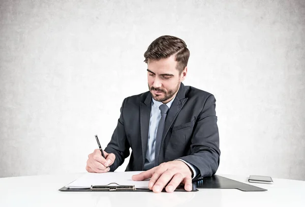 Serious businessman signing document at table — Stock Photo, Image
