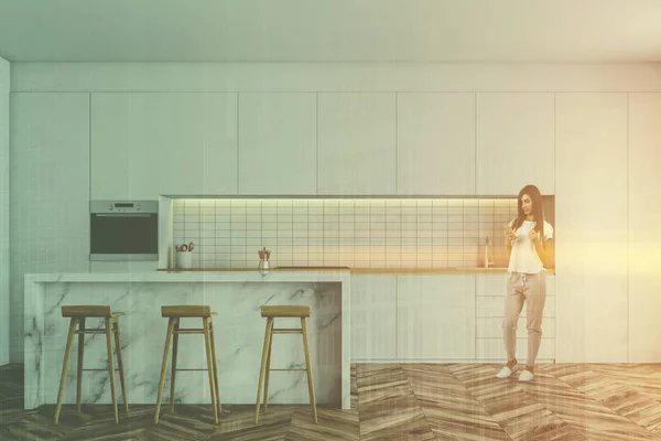Kvinna med telefon i vitt kök med bar — Stockfoto